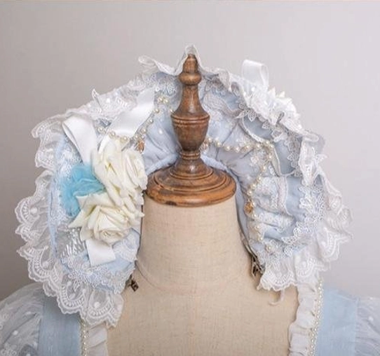 Light blue lolita lace bonnet headdress close-up showing ruffled white lace trim, 3D white rose and blue fabric floral decor, satin ribbon bow embellishment on mannequin