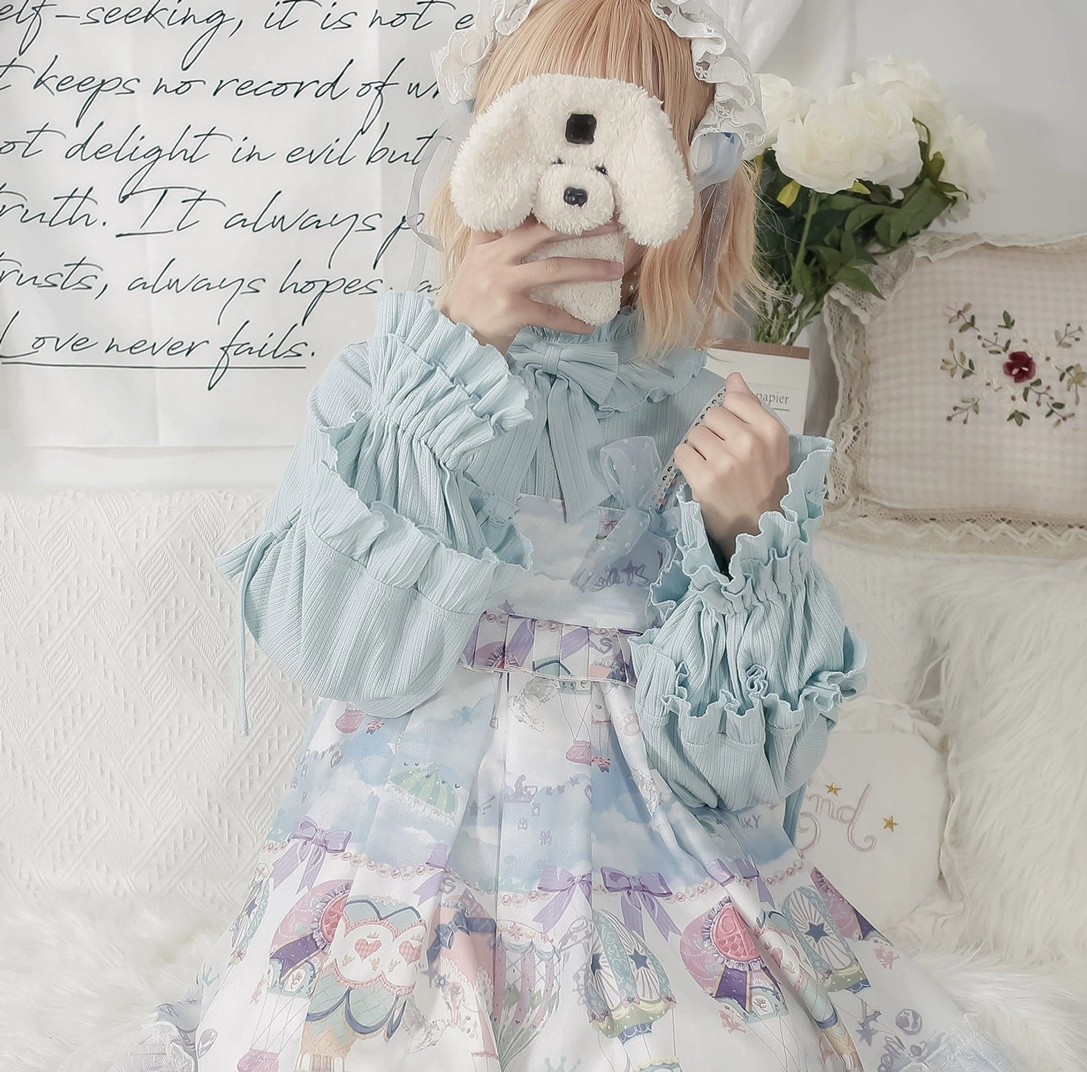 Light blue lolita knit inner shirt with bow neckline and layered ruffled sleeves styled with pastel lolita dress on furry sofa