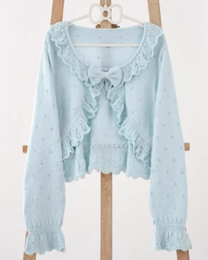 Light blue Lolita cropped knitted cardigan displayed on wooden hanger with ruffled collar, front bow decoration, and scalloped hem details