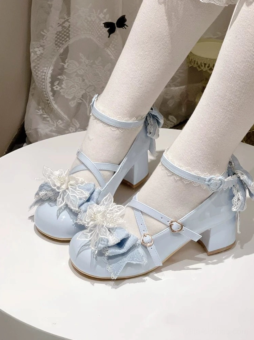 Light blue patent leather sweet Lolita mid-heels on display table with model wearing sheer lace stockings, flower and bow trims visible with chunky block heel and ankle strap bow detail