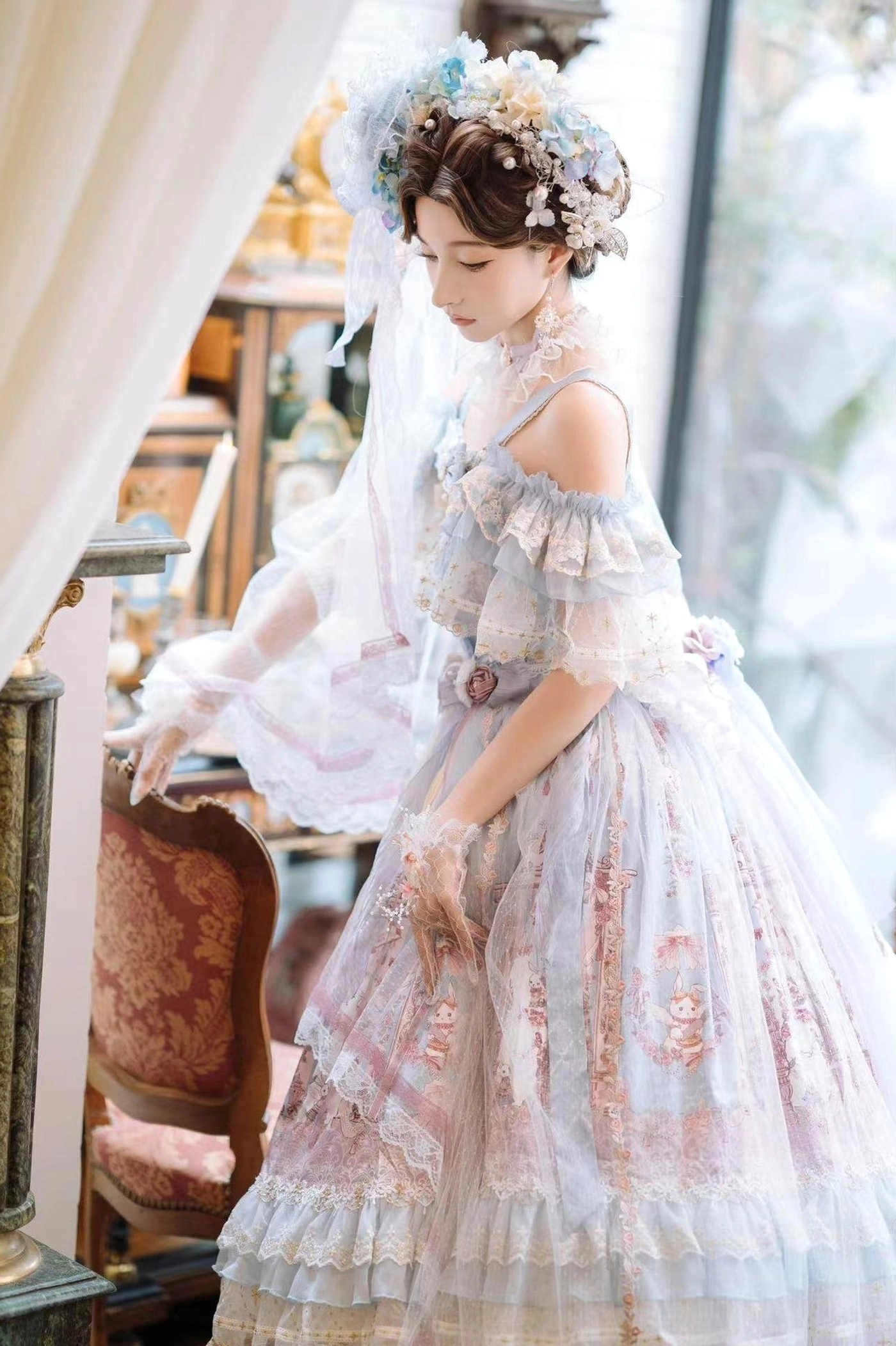 Light blue off-shoulder wedding Lolita JSK dress with sheer ruffled sleeves and embroidered floral prints, elegant long silhouette side view with vintage furniture