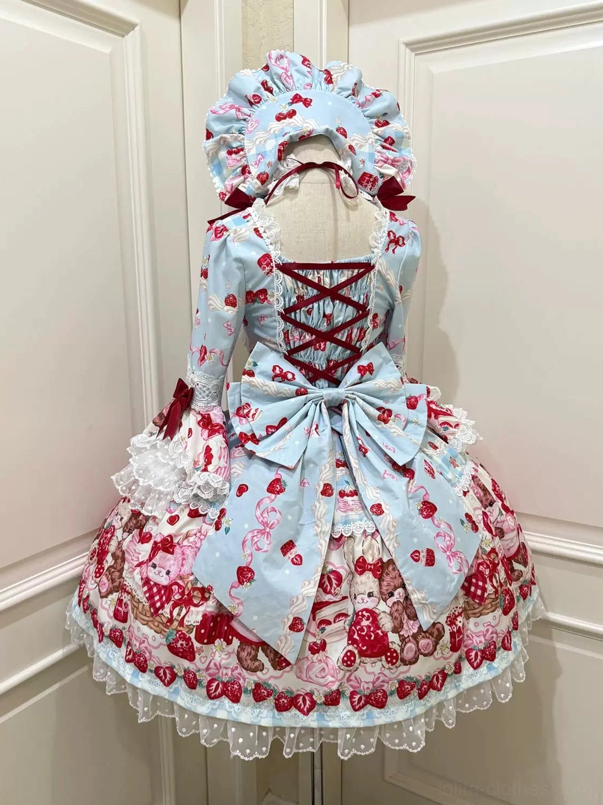 Light blue strawberry bear print lolita OP dress back view on mannequin with crisscross lace-up back, light blue satin waist bow, ruffled hem white lace trim and matching bonnet