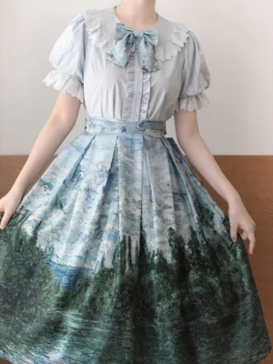 Light blue short-sleeve sweet lolita cotton blouse with ruffled Peter Pan collar and puff sleeves paired with vintage landscape print midi skirt back three-quarter view