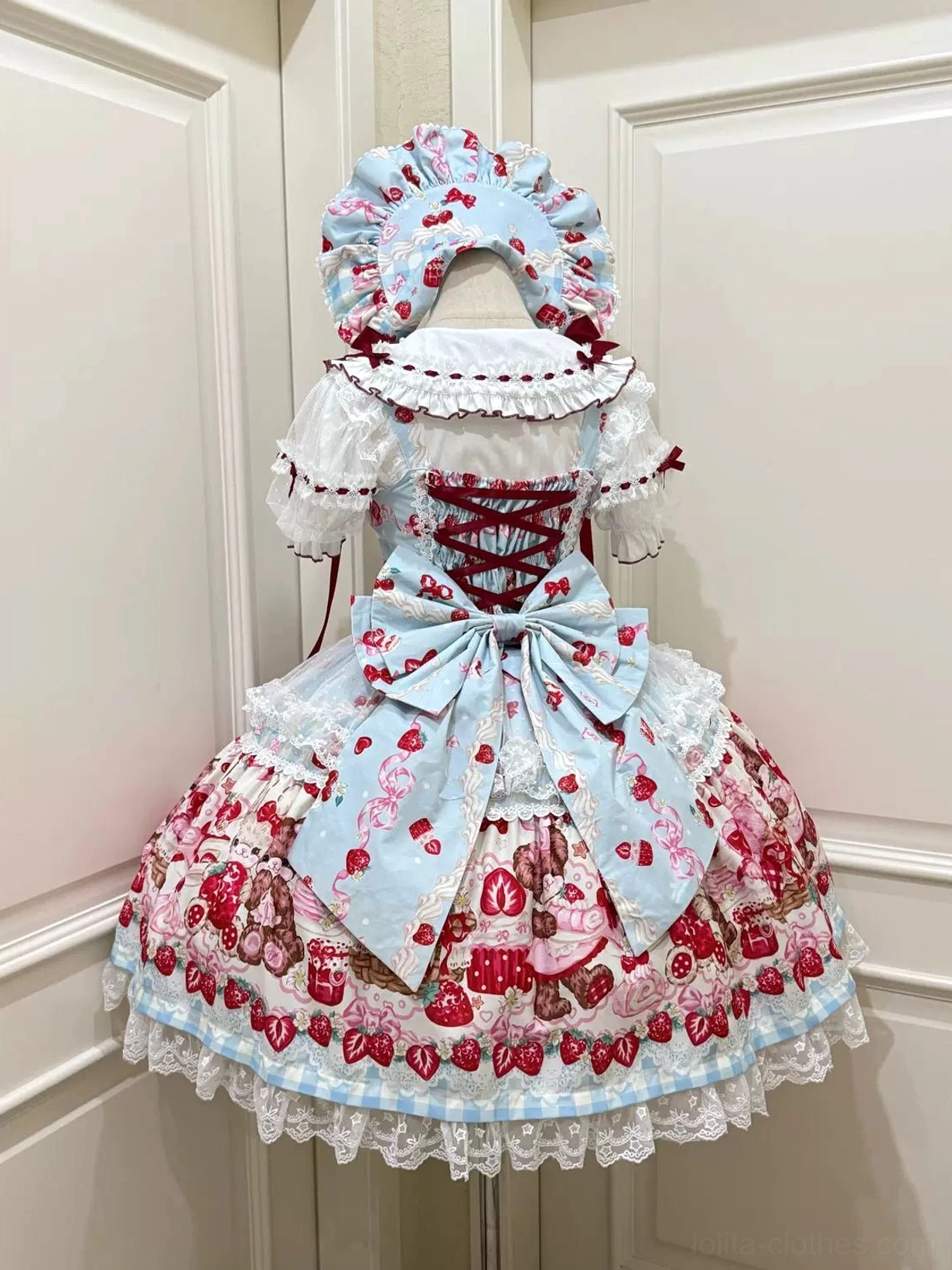 Light blue strawberry bear print sweet lolita JSK dress back view with trailing bow and lace-up bodice on dress form