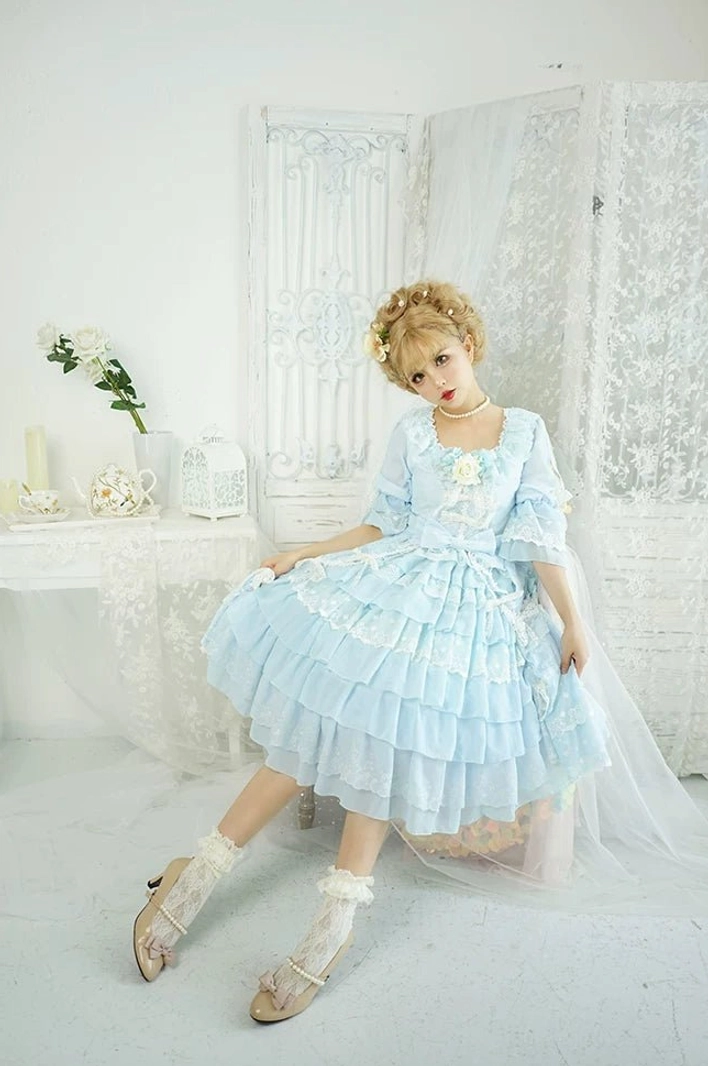 Light blue Sweet Lolita OP dress with vintage square neckline, tiered ruffle hem, lace trims, pearl choker, and vintage leather shoes with lace socks, sitting view