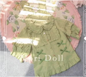Light green sweet lolita short sleeve blouse with decorative bows and ruffled sleeves, displayed on floral printed rug with natural sunlight