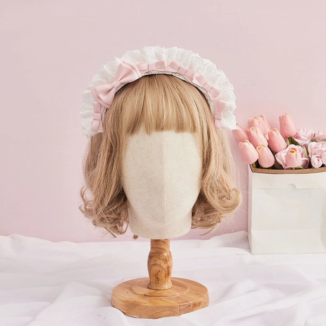 Light pink lolita lace KC headband modeled on mannequin head showing elegant satin bow and ruffled white lace edge design from front perspective