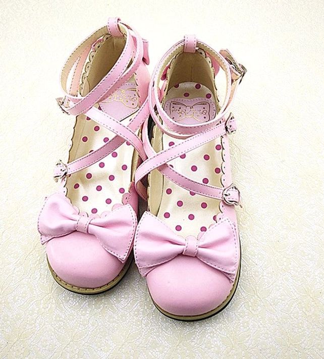 Light pink Lolita low heel princess shoes front view with cross pink ankle straps and buckles, prominent pink bow decoration, round soft toe cap, and polka dot inner sole design