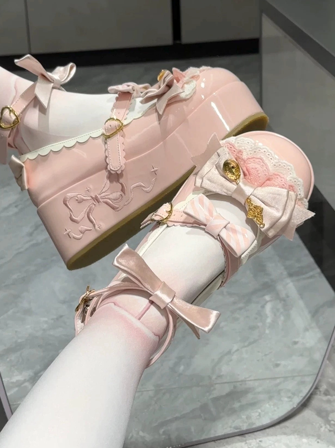 Light pink mousse roll sweet lolita platform shoes on feet close-up showing gold buckles ankle straps embroidered bow and patent leather upper
