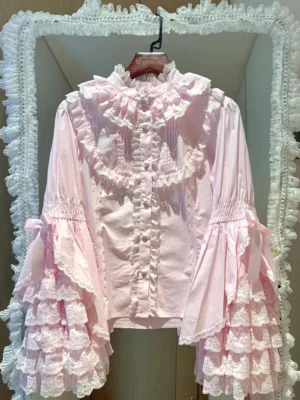 Light pink princess Lolita blouse with layered bell sleeves and heart-shaped pearl buttons, front view on vintage lace mirror backdrop