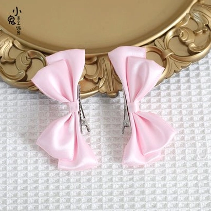 Light pink Sweet Lolita satin bow hair clips pair flat lay display showing soft pink satin bows with secure metal clip mechanism and elegant bow silhouette