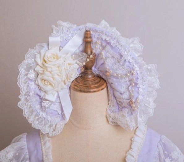 Light purple lolita lace bonnet headdress featuring ruffled white lace trim, 3D white rose floral decor, and satin ribbon bow accent on dress form display