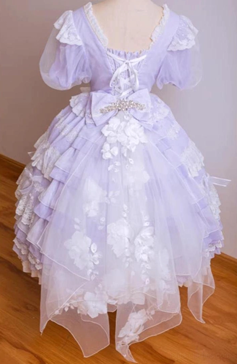 Light purple classic lolita dress back view displaying lace-trimmed square back neck, large waist bow, layered skirt with 3D white floral sheer tulle overlay and irregular handkerchief hem detail