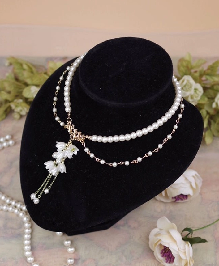 Single lily flower pendant pearl necklace showing mixed chain styles smooth pearl strand and fine gold chain with elegant lily pendant and dangling pearls three-quarter front view on display stand