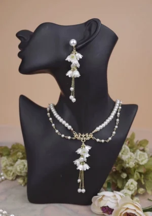 Lily pearl Lolita necklace and cascading tassel earrings shown on mannequin neck close-up view showcasing dual-layered chain design with gold-tone hardware and pearl accents against floral backdrop