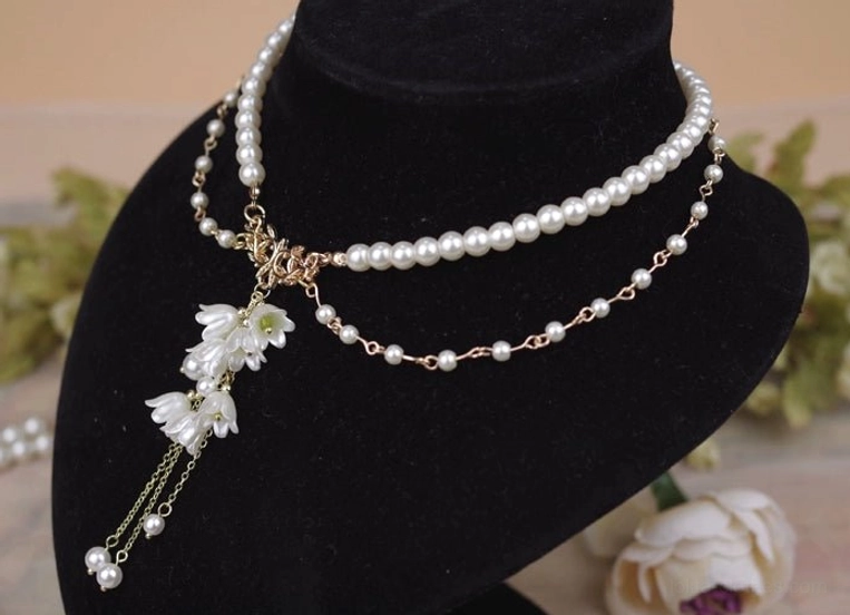 Side view of lily pendant pearl necklace demonstrating asymmetrical layered chains gold metal hardware and delicate lily tassel with pearl drop ends three-quarter angle display