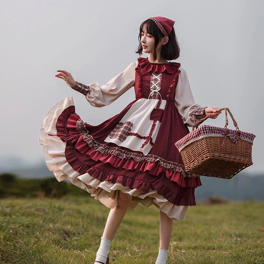 Little Red Riding Hood pastoral Lolita OP dress full-body front three-quarter view with tiered ruffled skirt, mutton sleeves, and wine red ice silk crepe bodice, worn by model in outdoor grassland meadow setting