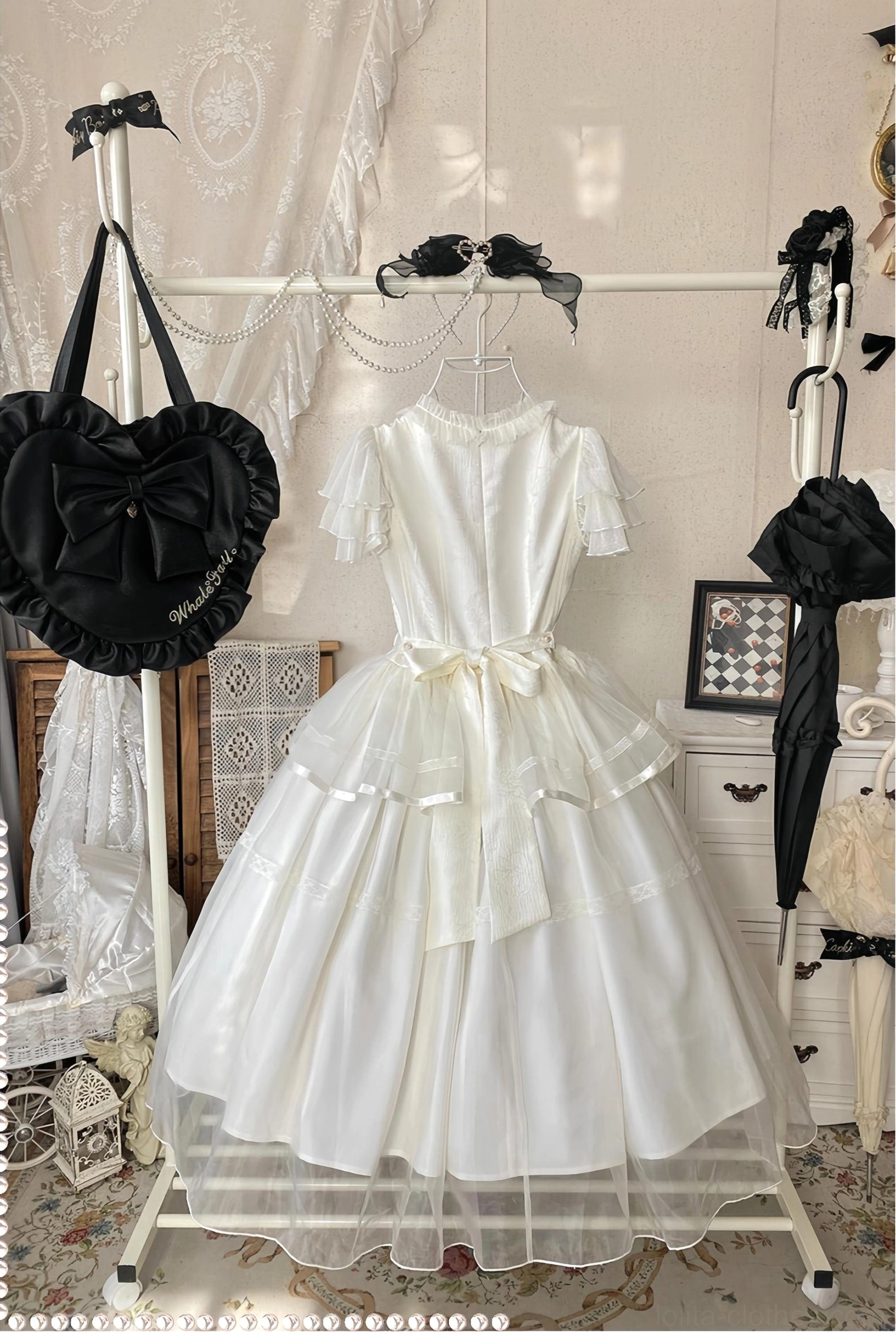 Ivory embroidered tulle classic lolita OP dress on clothing rack showing satin waist sash, layered tulle hem, and ruffled neckline detail