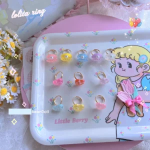 Multiple pastel heart and seashell resin Lolita rings flat lay display with cartoon girl dessert tray