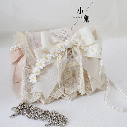 Ivory lace lolita handbag with light pink panels and detachable metal chain strap, front right oblique view gray background