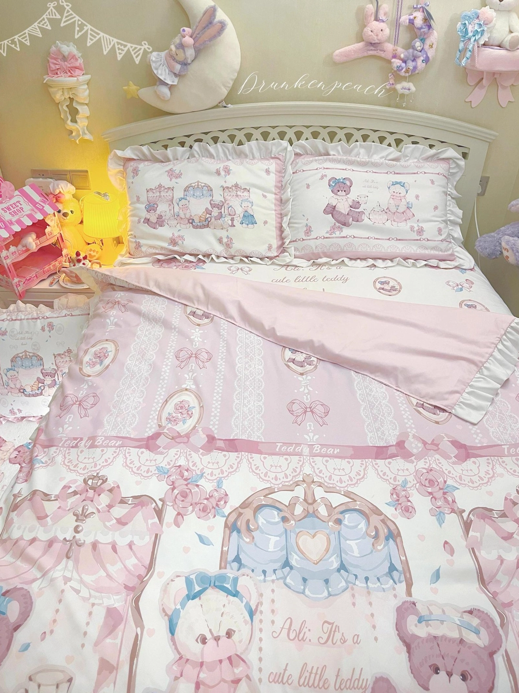 Three-quarter side view of lolita bear themed bedding set with bed runner, ruffled pillow shams, reversible print designs, and bow-inspired lace accents in warm lighting