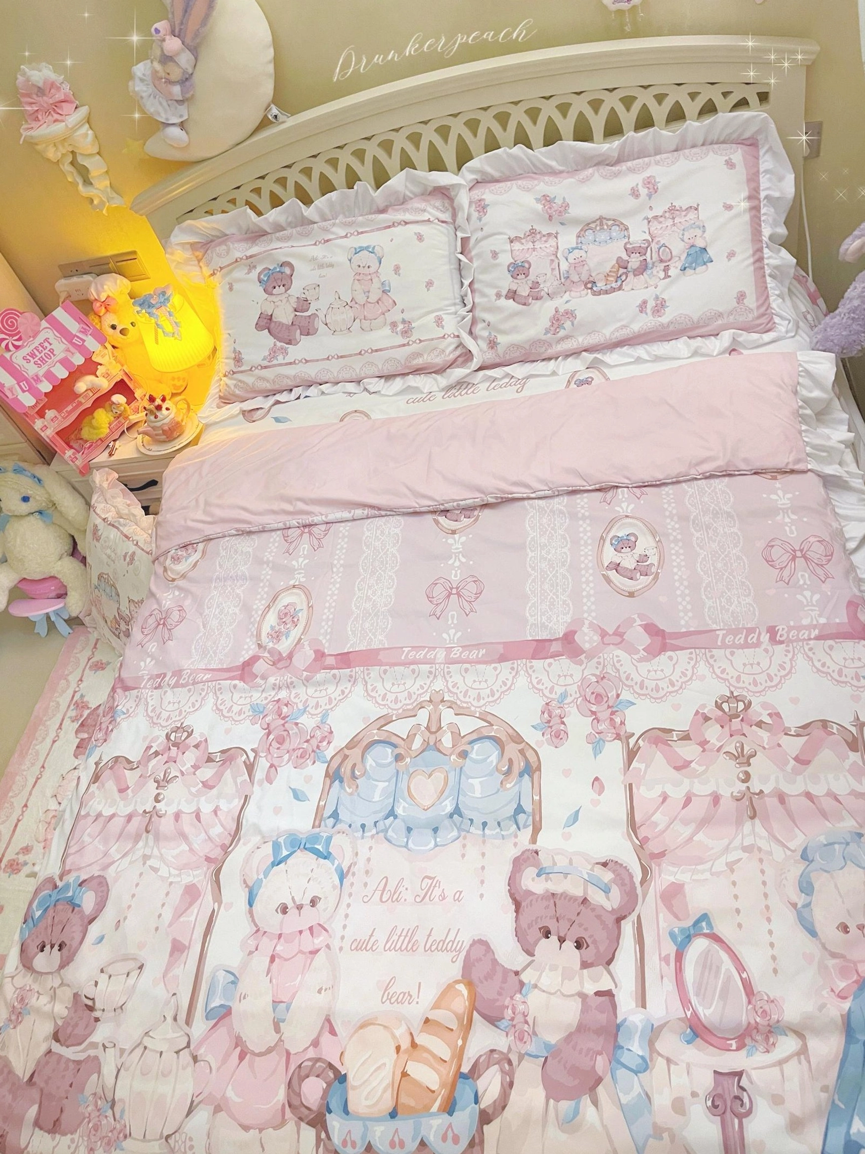 Close-up detail of lolita bear bedding pillows and sheet showing ruffled pillow edges, circular bear medallion prints, bow pattern bed sheet, and English slogan text on fabric