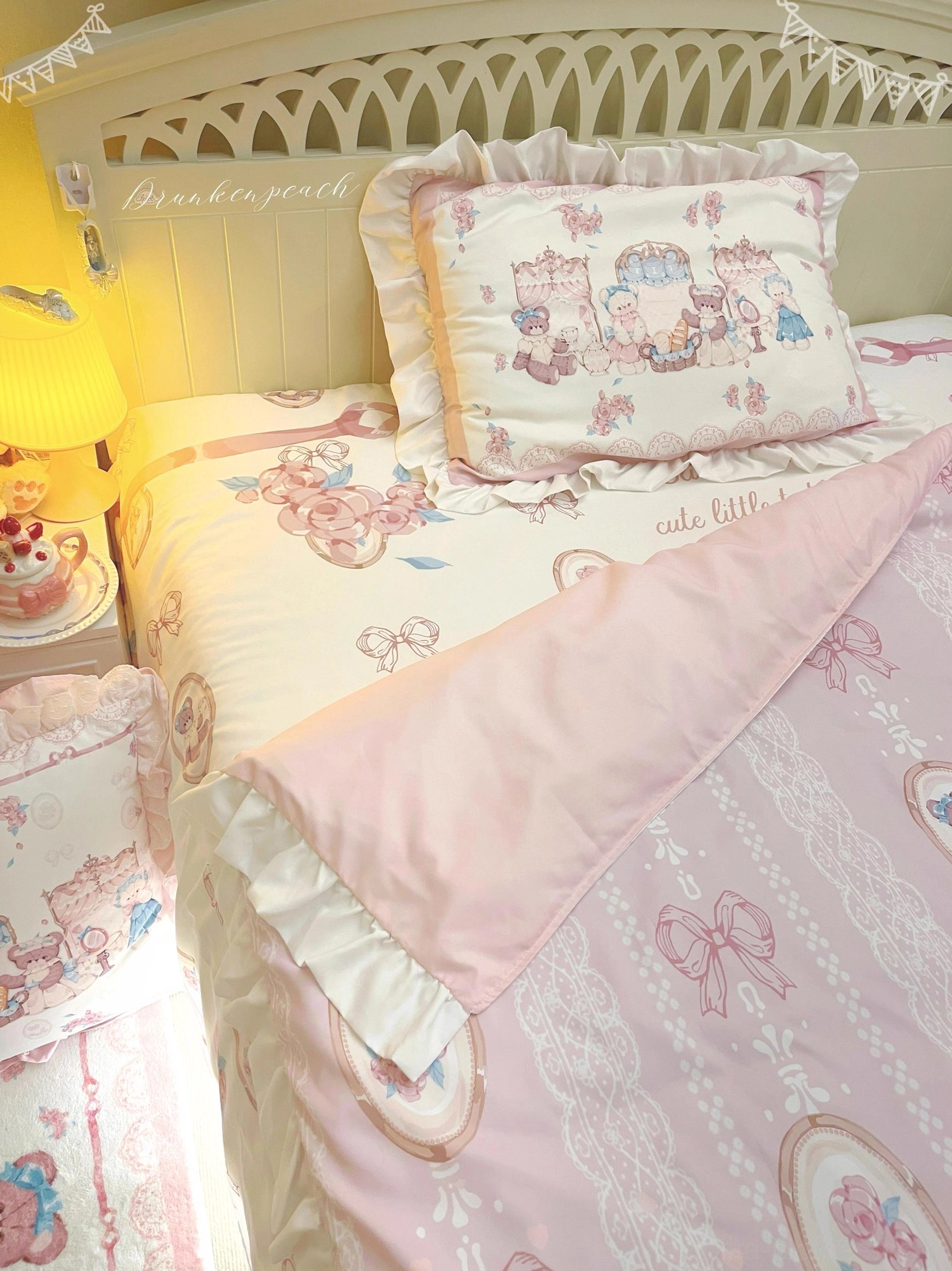 Close-up detail of lolita bedding set showing ruffled pillow shams with intricate bear tea art prints, lace-patterned bed fabric, and circular bear medallion motifs in cozy bedroom