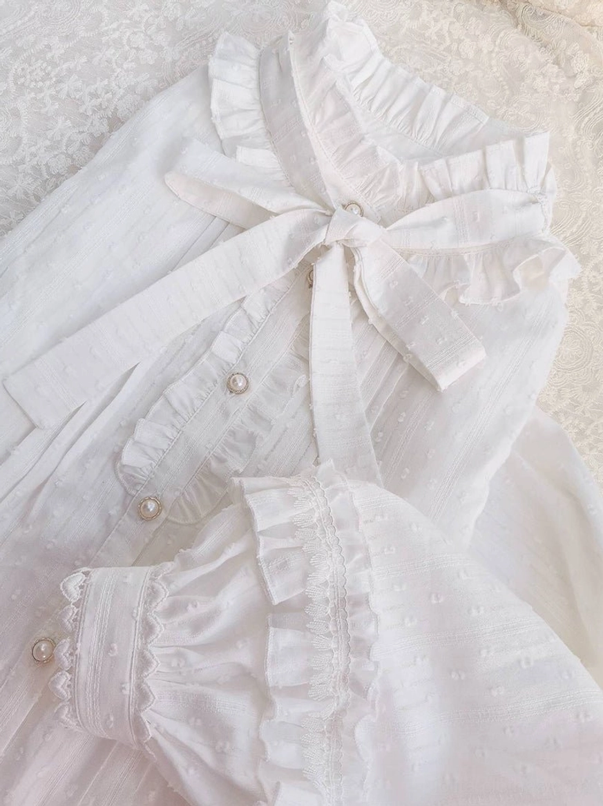 Angled overhead flat lay lolita blouse detachable neck bow ruffled bishop cuffs pearl buttons textured dotted woven fabric