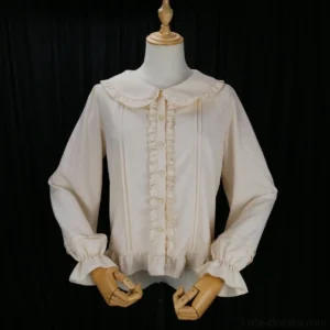 Apricot beige lolita long-sleeve blouse with peter pan doll collar, puff sleeves, ruffled trim, and decorative buttons displayed on vintage wooden mannequin