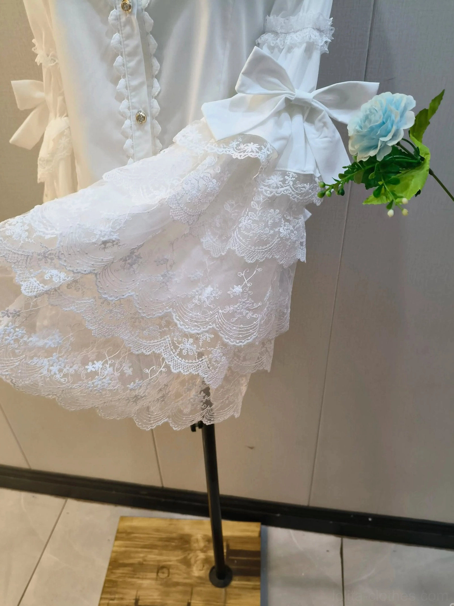 Close-up of multi-layered bell sleeve with floral embroidered lace ruffles, satin cuff bow, and wavy ruffled lace edges on lolita blouse