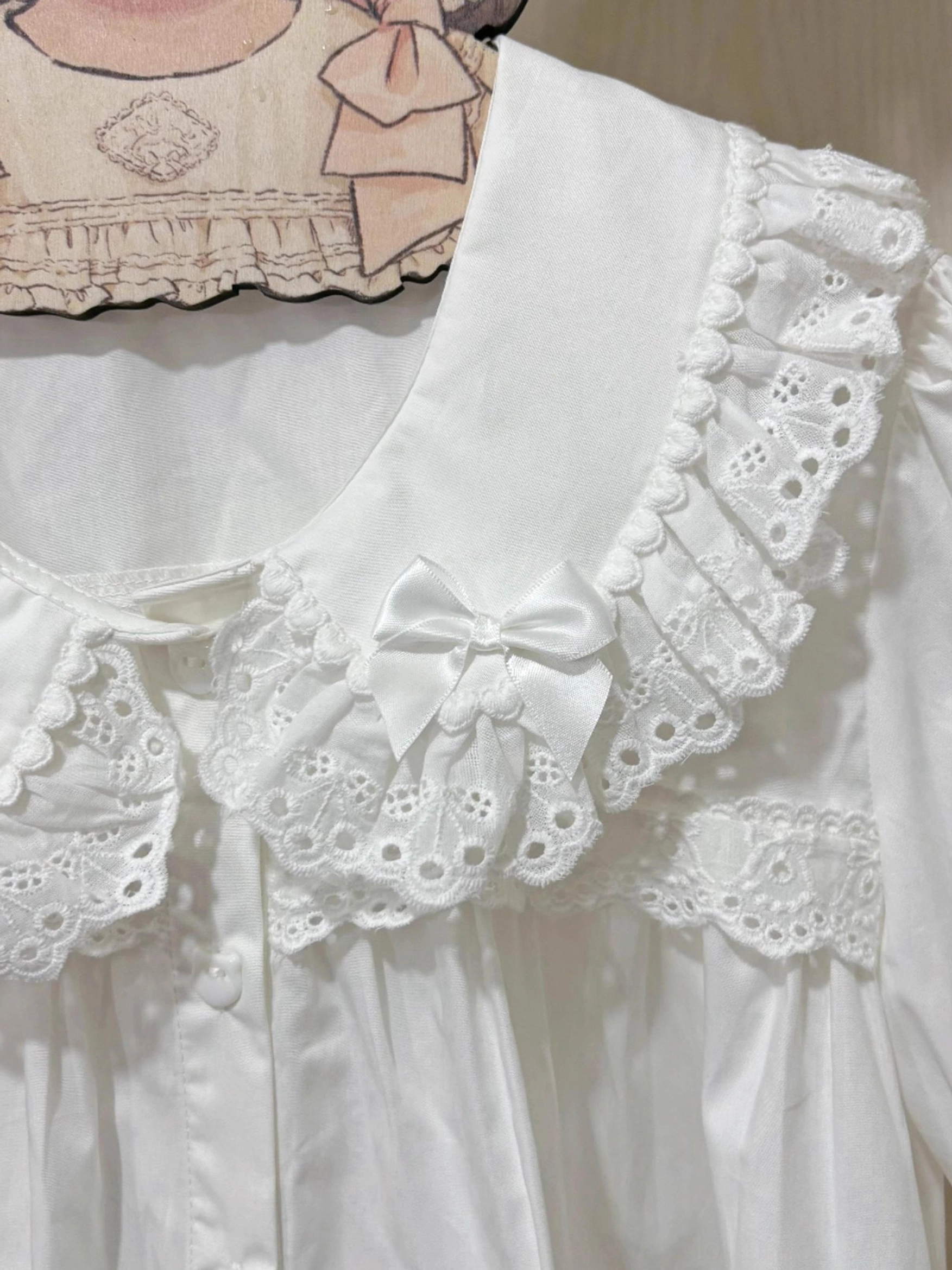 Extreme close-up detail of lolita blouse peter pan collar featuring double-layered scalloped lace embroidery, tiny satin bow decoration, hollow embroidered lace trim craftsmanship