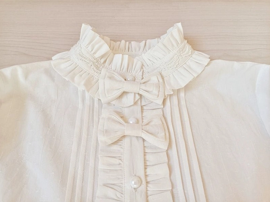 Close-up detail of lolita blouse ruffled stand collar with double fabric bows and pleated ruffle placket