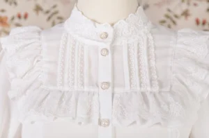 Close-up detail of princess sleeve lolita blouse collar and front yoke featuring stand collar, decorative pearl buttons, pleated lace panels and ruffled trims on lightweight chiffon fabric