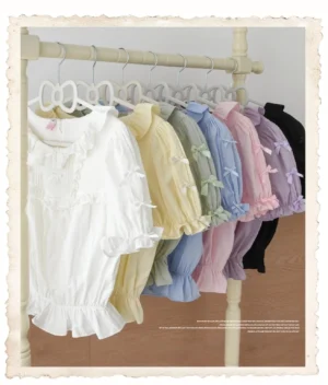 Multiple solid-color lolita short-sleeve blouses displayed on clothing rack, featuring ruffled trims and puff sleeves in pastel color options