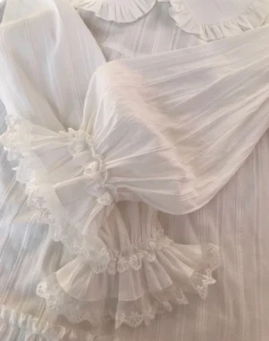 Close-up detailed view of pleated ruffle doll collar and double layer lace cuffs of white lolita blouse showing sheer vertical stripe texture