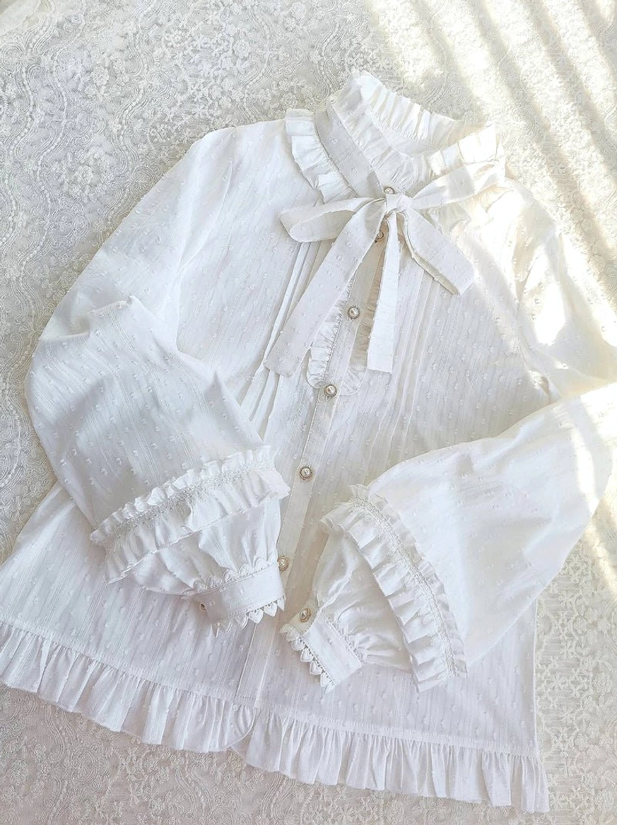 Lolita blouse flat lay overhead sunlight shadows lace background ruffled hem detachable bow ruffled cuffs pearl placket