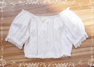 flat lay of white cropped Lolita blouse showing off-shoulder neckline gathered bodice lace trim and front bow detail