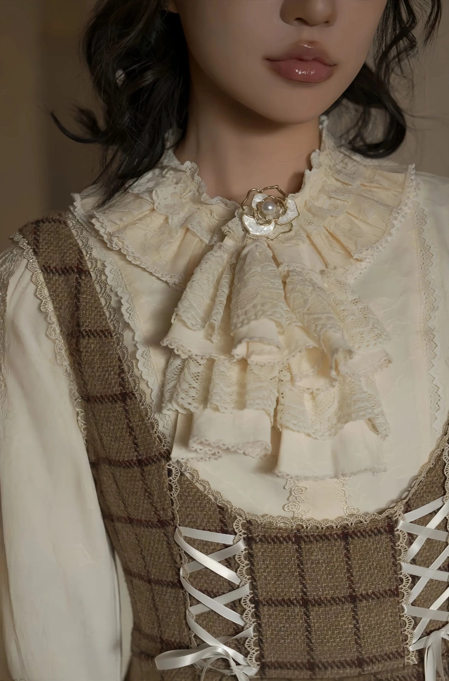 Close-up detail of classic lolita blouse neckline showing heart-shaped brooch on layered ruffled lace jabot collar with delicate embroidered accents