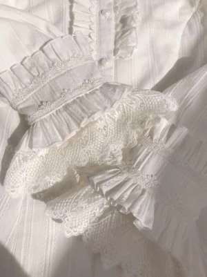 Close-up detail of multi-layer embroidered lace ruffled cuffs and pearl button front placket of Sweet Lolita blouse