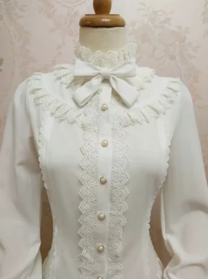 White stand collar Lolita blouse medium torso shot displaying lace yoke detailing central pearl button placket and detachable neck bow with long sleeves