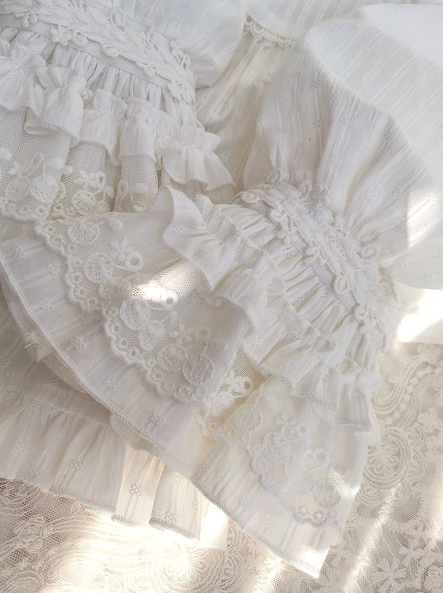 Detailed overhead close-up of multi-layered lace ruffles, shirred wrist details, delicate embroidered lace applique, and soft matte cotton texture on lolita blouse collar and cuff elements