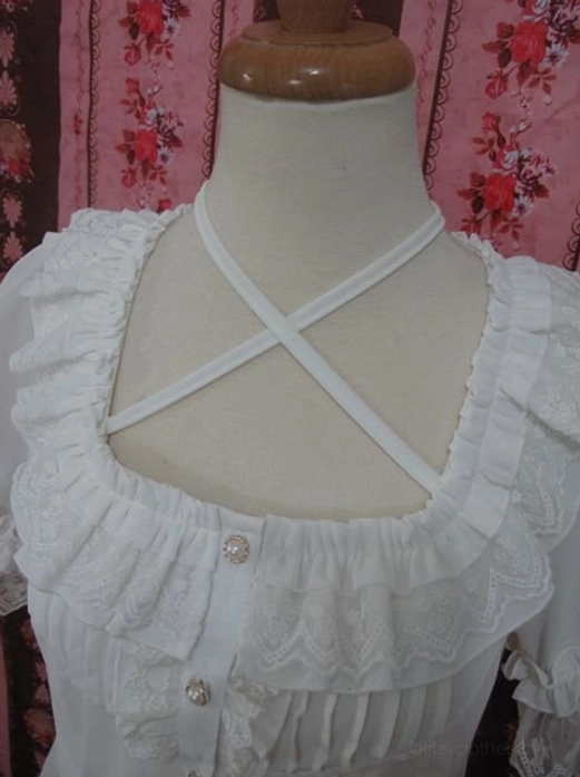 Front close-up of neckline detail showing double-layer lace ruffled square collar with crossover halter straps and pearl buttons