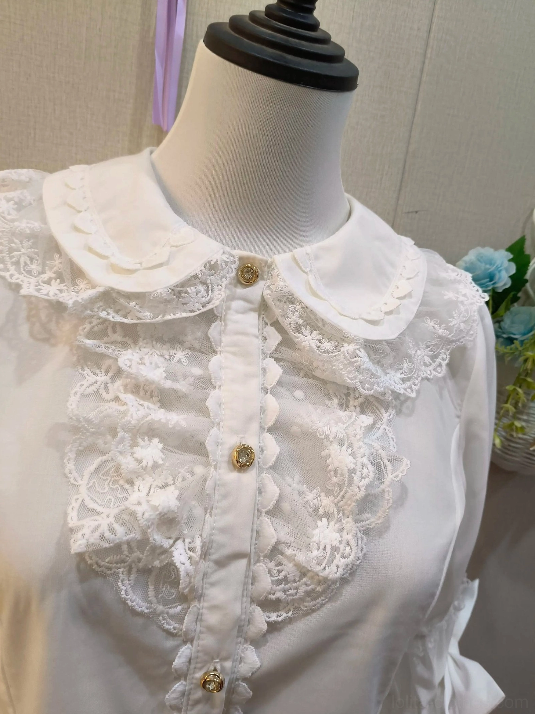 Close-up detail of white lolita blouse neckline and placket, showing scalloped doll collar, embroidered lace chest frills, and gold decorative buttons