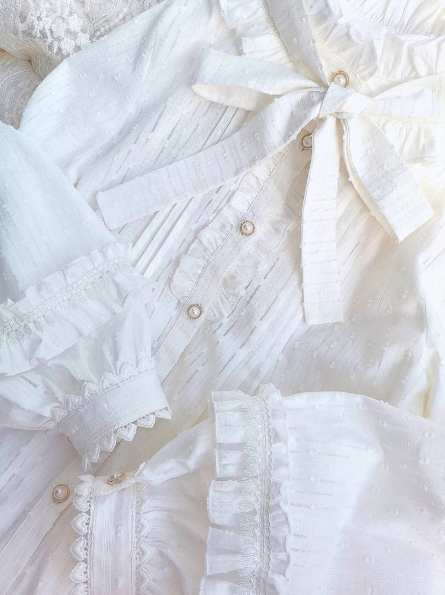 Lolita blouse close-up overhead view large neck bow tie pearl buttons ruffled cuff trim pleated front dotted cotton fabric