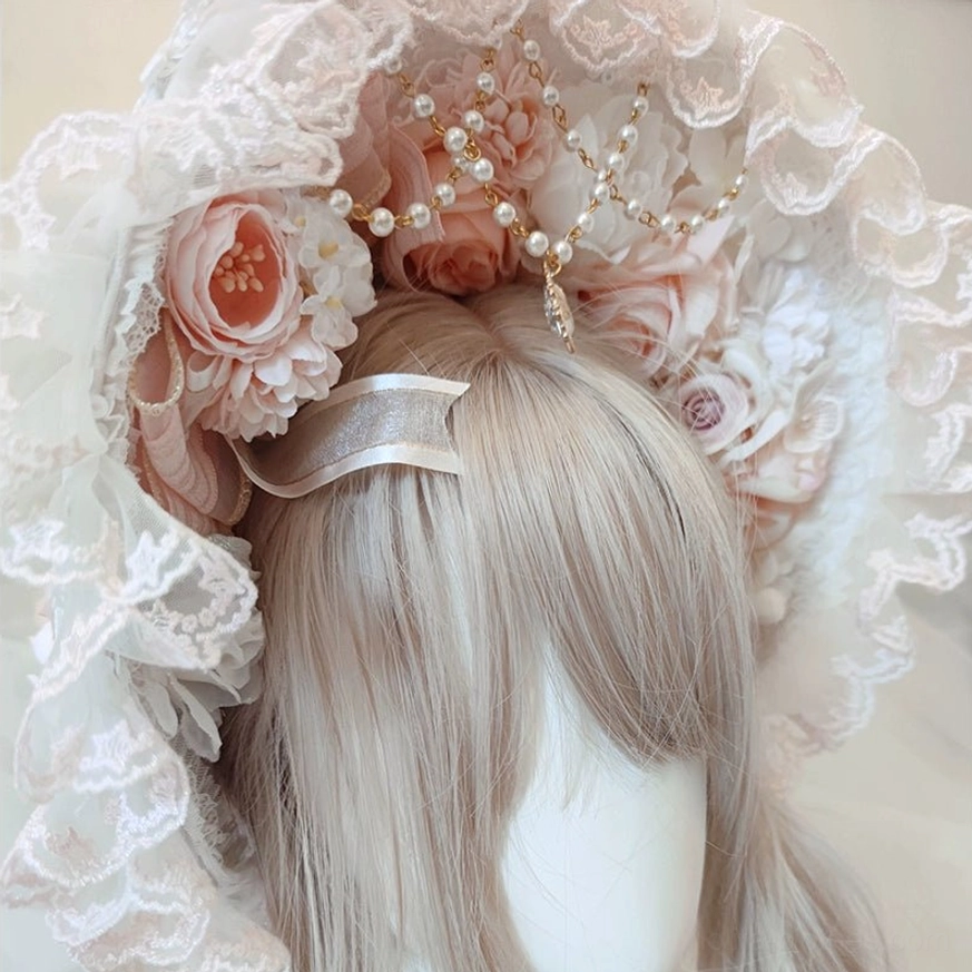 Elegant Lolita lace bonnet headdress close-up with ruffled lace trim, artificial peach roses, pearl and gold gem ornaments, displayed on mannequin with ash blonde wig and silver hair clip, frontal view