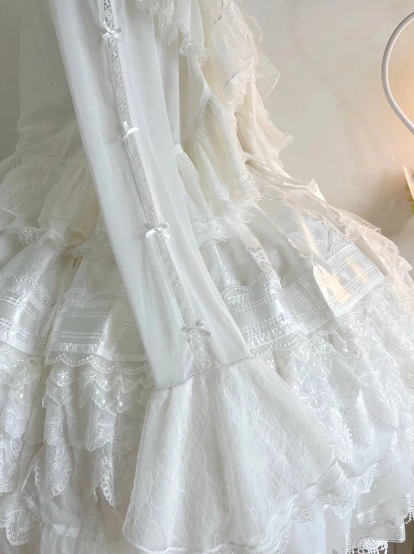 Low-angle close-up of lolita bolero cardigan hem and skirt, layered tiered lace and ruffle designs decorated with small satin ribbon bows