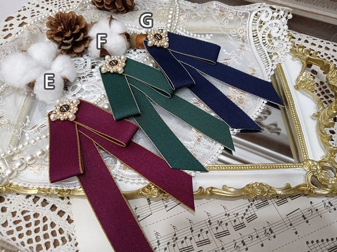 overhead-flat-lay-lolita-bow-brooch-three-colors-wine-red-forest-green-navy-blue-gold-ribbon-trim-flower-shaped-pearl-bead-ornament-vintage-gilt-frame-sheet-music-backdrop