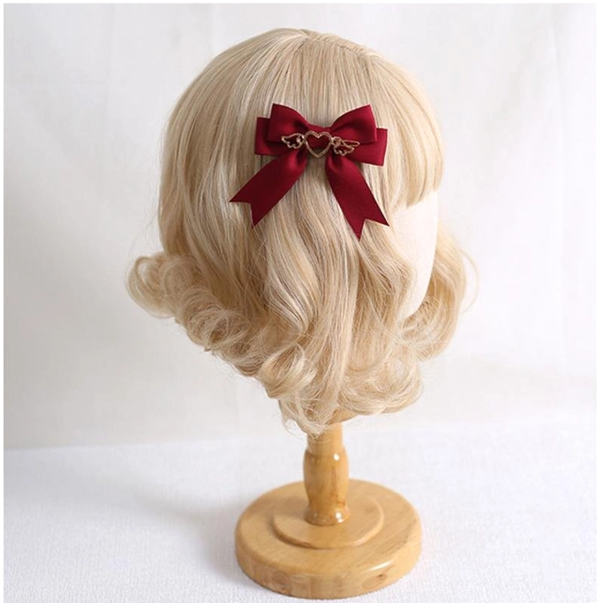 Detailed view of lolita bow clip satin ribbon texture and gold heart-wing metal charm craftsmanship