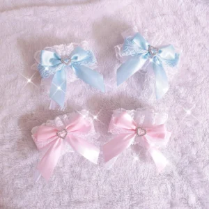 Lolita bow wrist cuffs collection flat lay showing four pieces in sky blue and baby pink with intricate lace edges and heart-shaped rhinestone decorations on sparkly plush fabric background