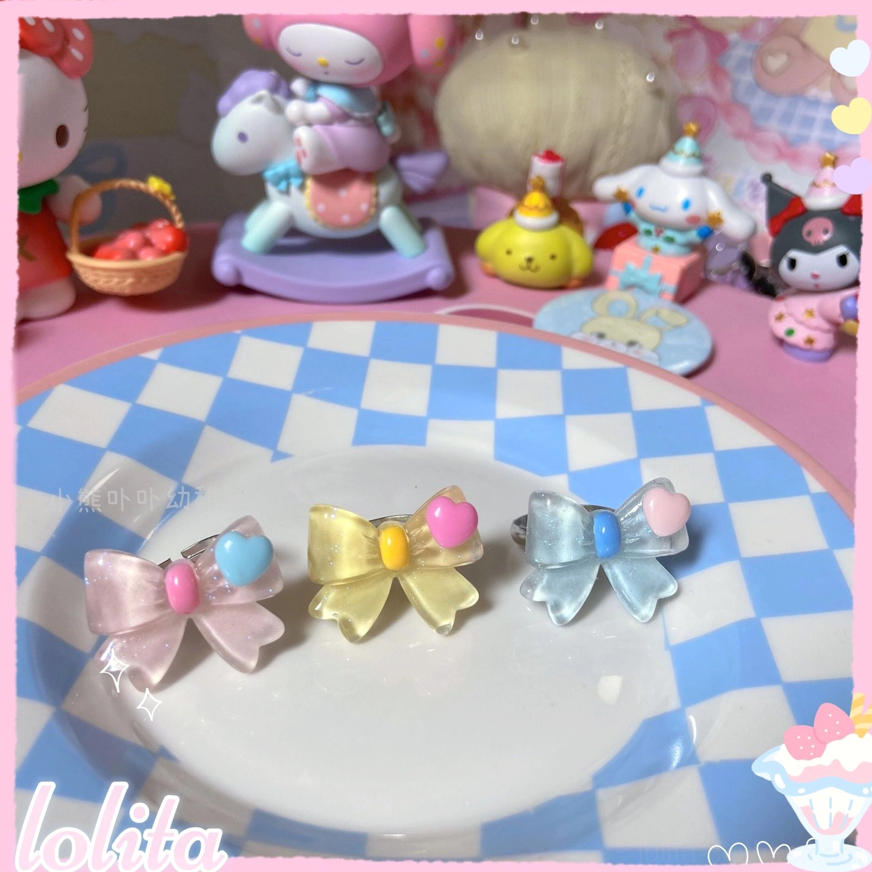 Three styles of sweet lolita bowknot adjustable rings in pink yellow and blue with heart-shaped resin accents and shiny metal ring bands on checkered plate